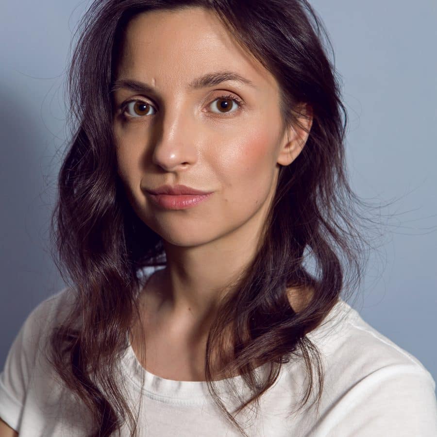 retrato de una mujer morena con una camiseta de fondo azul x